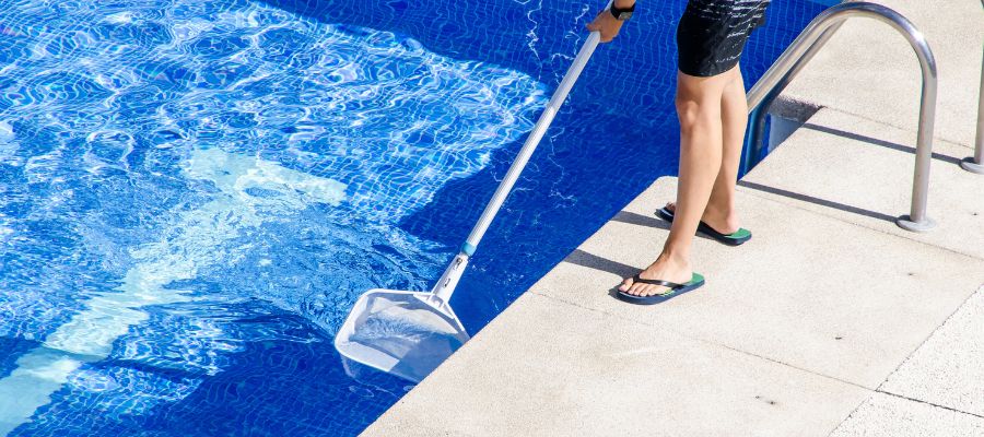 Boy in flip flop cleaning the swimming pool